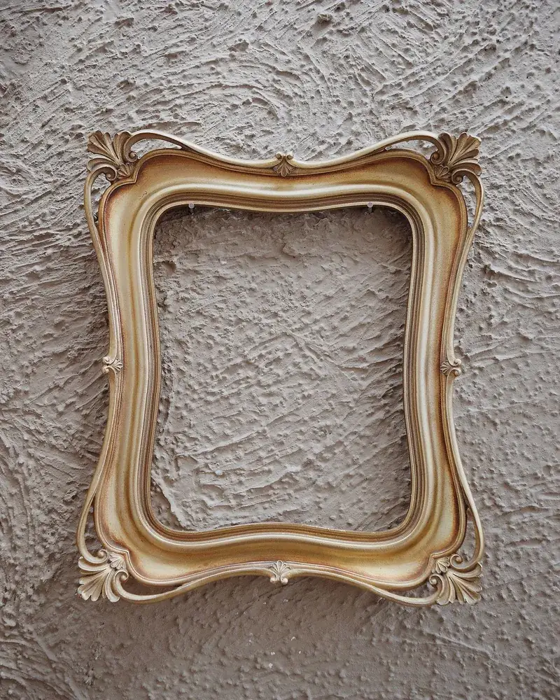 Detalle del ángulo de un marco antiguo dorado con ornamento en relieve sobre pared texturada